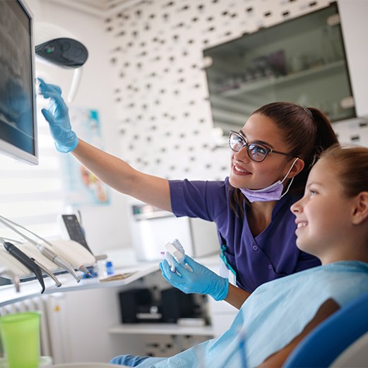 Child and dental team member looking at chairside computer screen