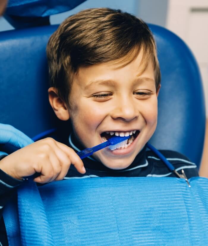 Child in dental chair practicing tooth brushing