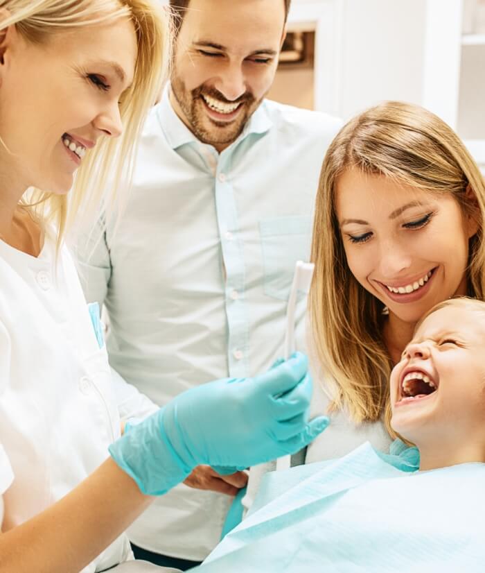 Parents and child laughing with dental team member