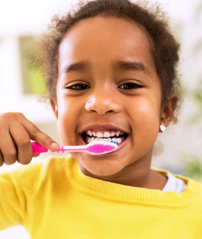 Child brushing teeth and engaging in at home dental care
