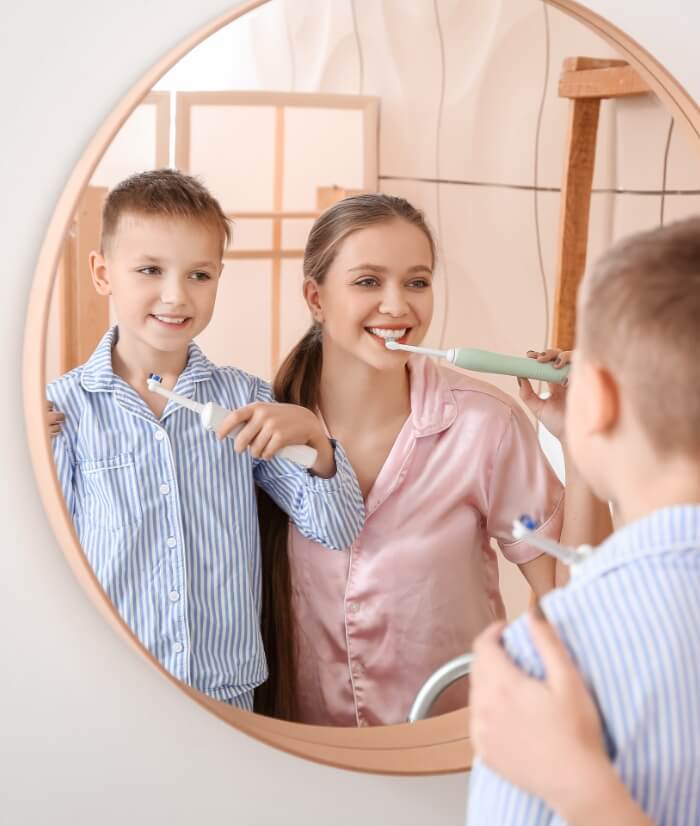 Mother and child brushing teeth after at home teeth whitening treatment