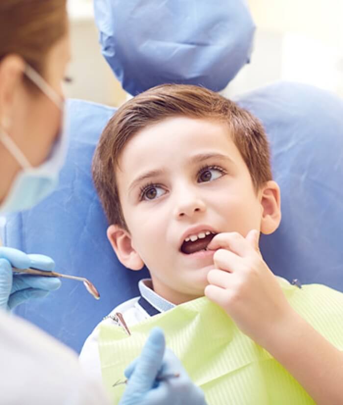 Child pointing to smile during children's dentistry visit