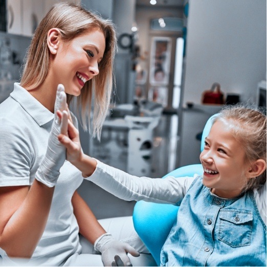 Child giving dental team member a high five while visiting the pediatric dentist in Papillion Nebraska
