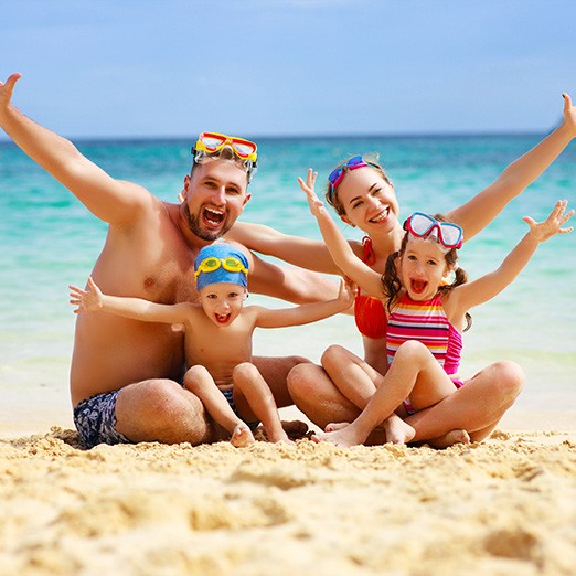 Family of four smiling at the beach