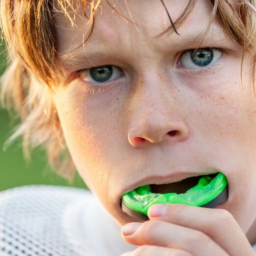 Young patient placing a custom athletic mouthguard