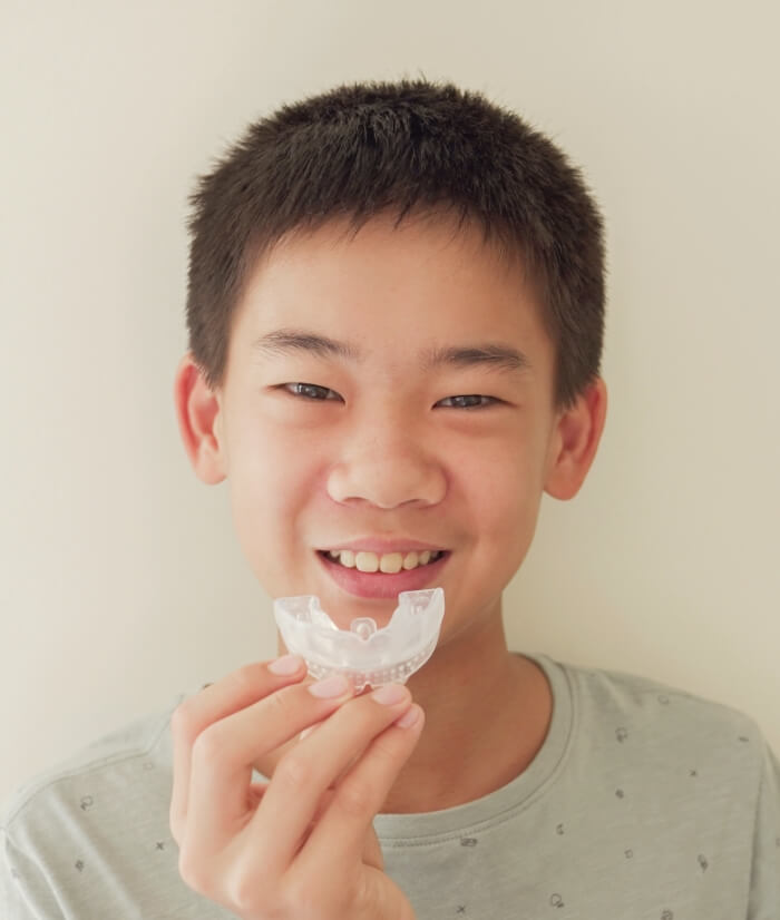 Pretten boy placing a custom mouthguard