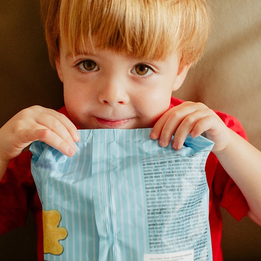 Little boy holding up unopened package of food