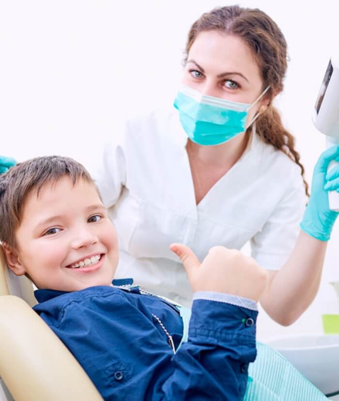 Child giving thumbs up after pulp therapy treatment