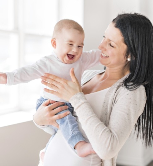 Mother holding infant after lip and tongue tie screening