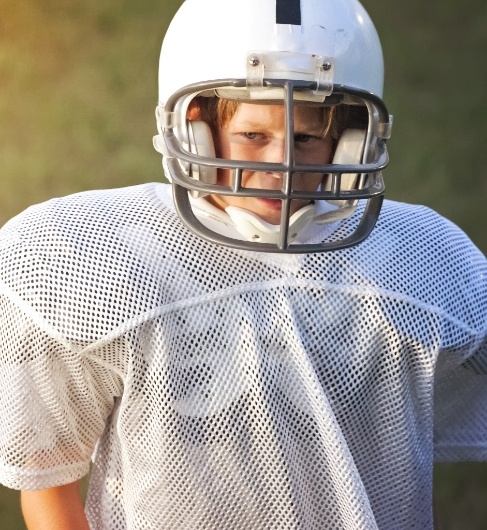 Child wearing athletic mouthguard and football equipment