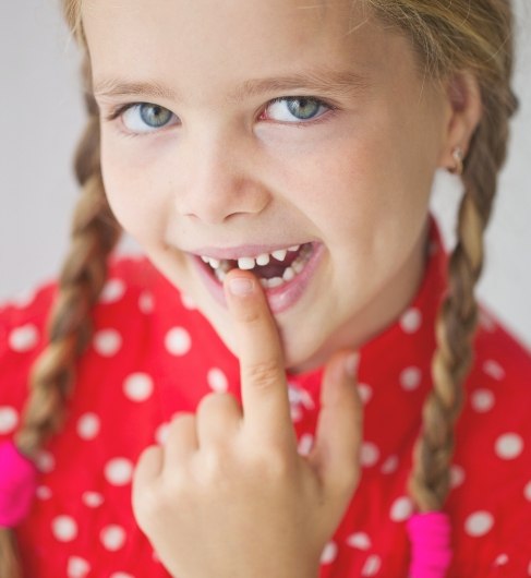 Child pointing to smile after tooth extraction