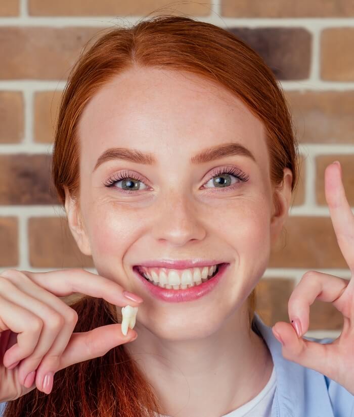 Woman holding up tooth after extraction