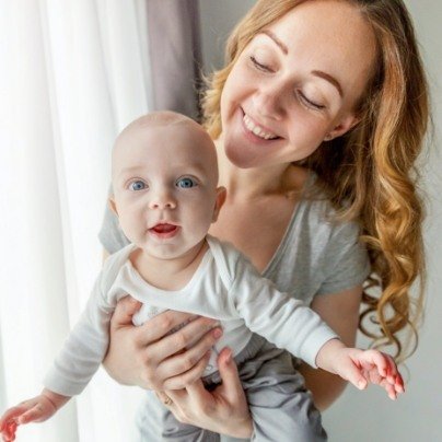 Mother holding smiling baby after visiting the dentist for infant in Papillion Nebraska