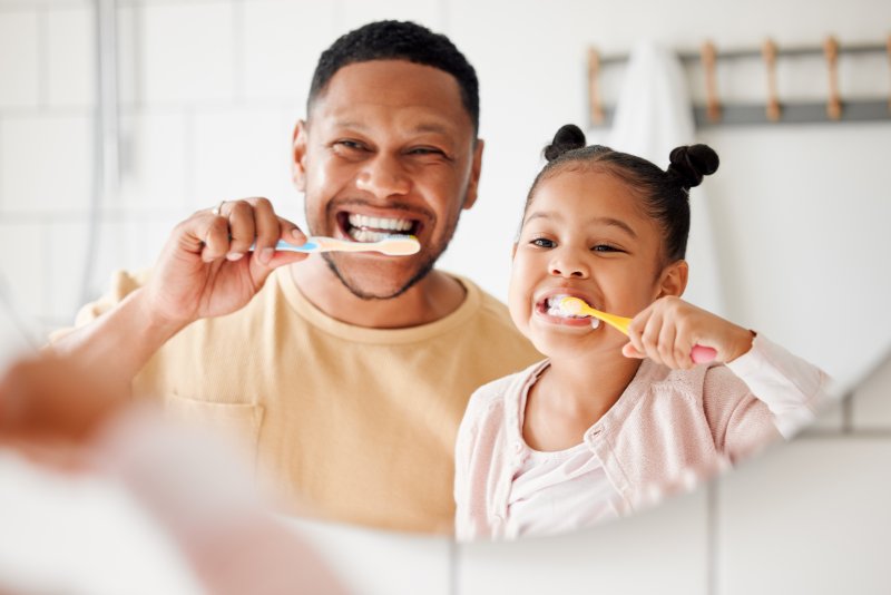 child brushing their teeth with their parent