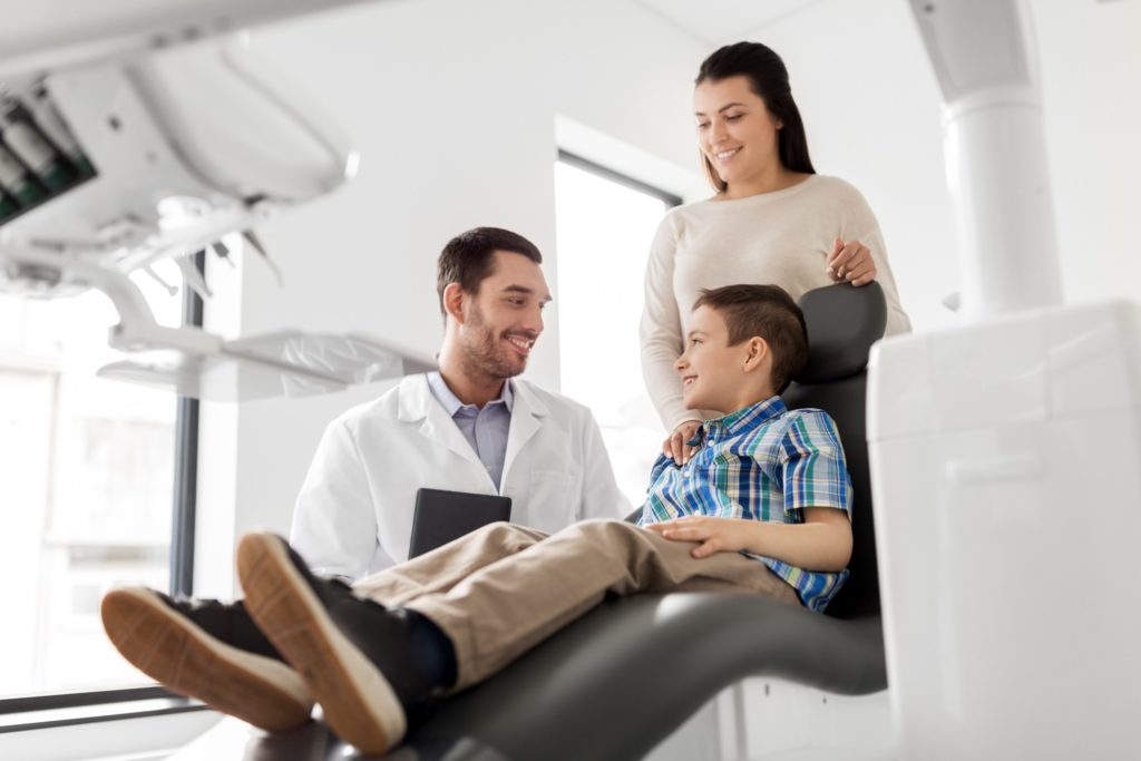 Mom and son smiling while talking to dentist