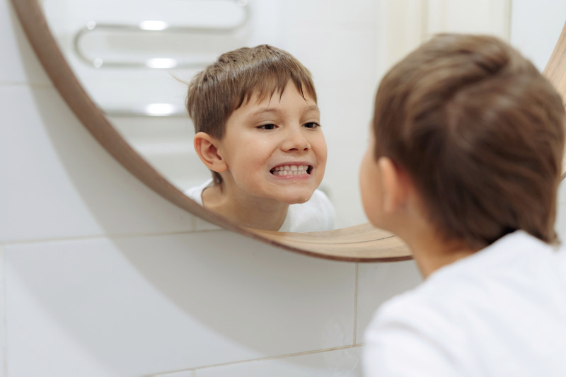 Young patient smiling in the mirror after teeth whitening