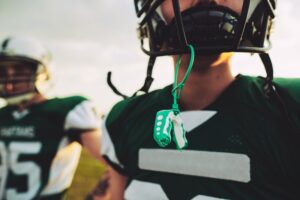 Young football player with mouthguard hanging from facemask. 