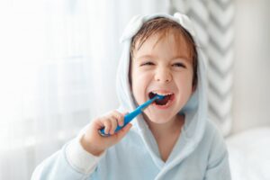 Kid brushing teeth with big smile.
